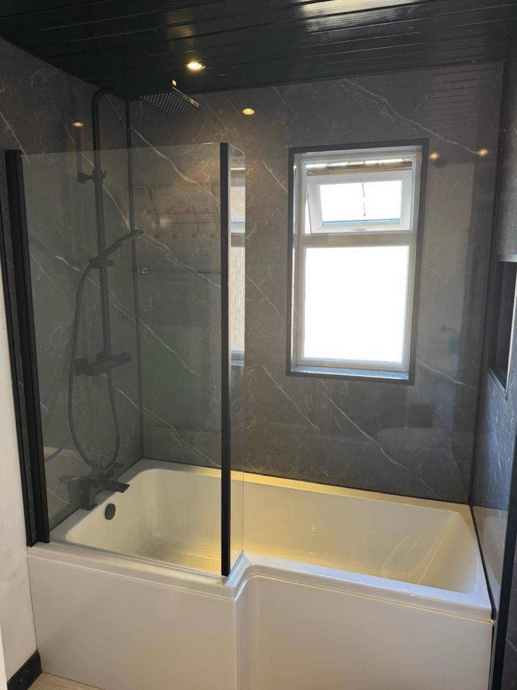 After: shower bath with marble-effect panels and matt black fittings