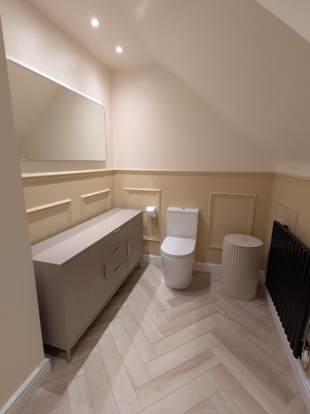 Panelled bathroom with herringbone floor and black radiator
