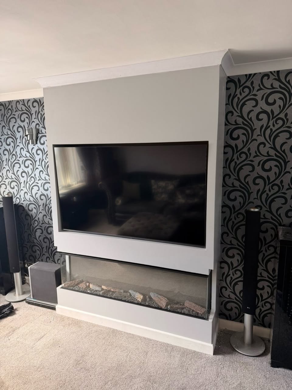 After: full-height media wall with recessed TV and fire below
