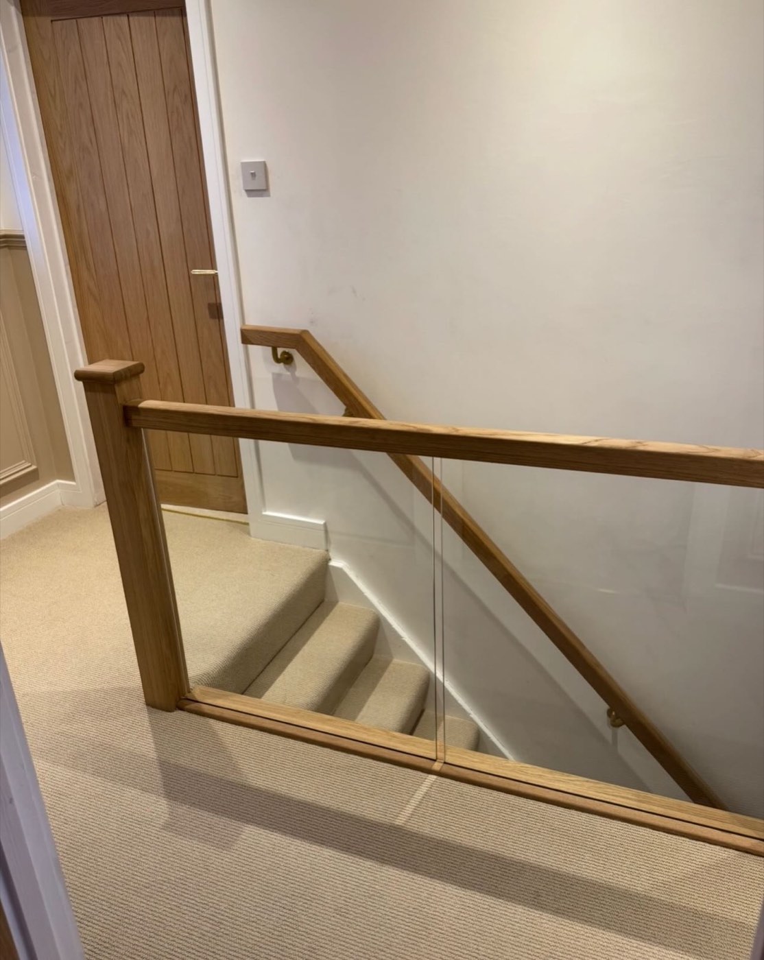 After: oak banister with glass panels on a bright landing