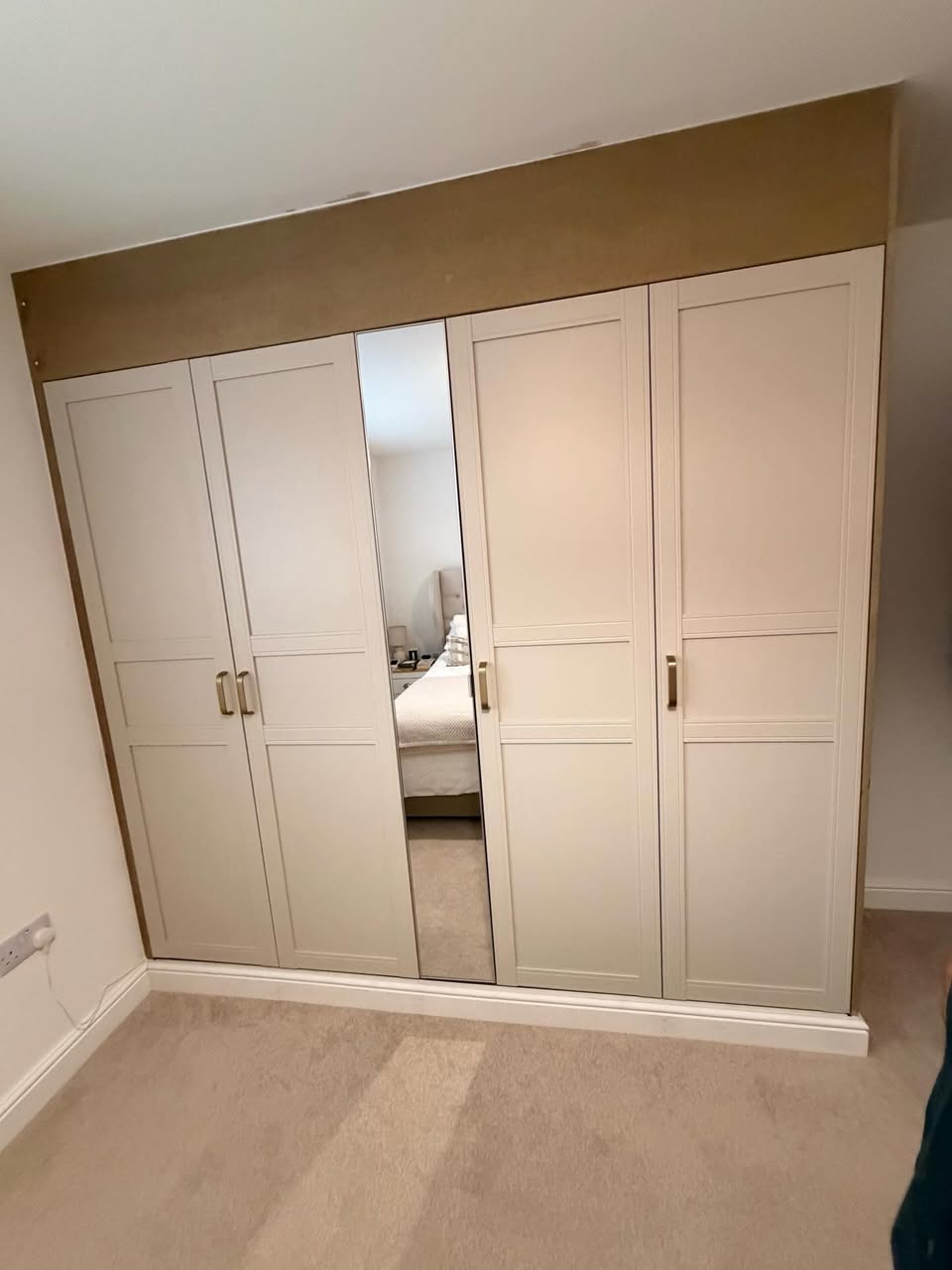 Fitted white shaker wardrobes with a mirrored centre door